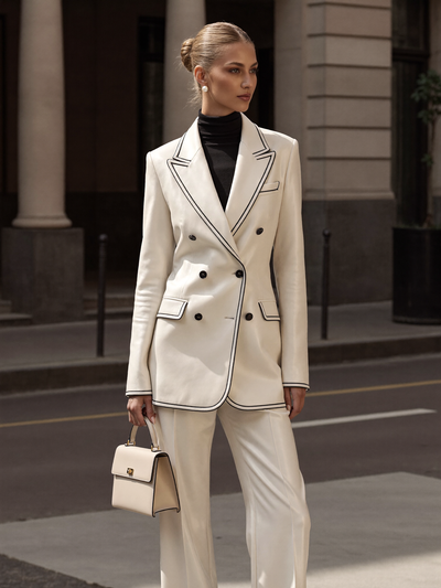 Woman wearing a cream double-breasted blazer and trouser suit over a black turtleneck on a city street
