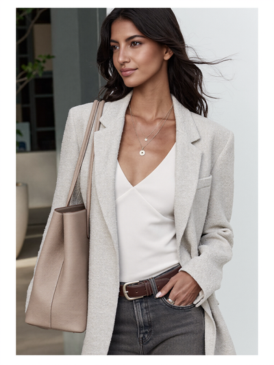 Woman wearing a beige blazer over a white camisole, carrying a taupe leather tote bag